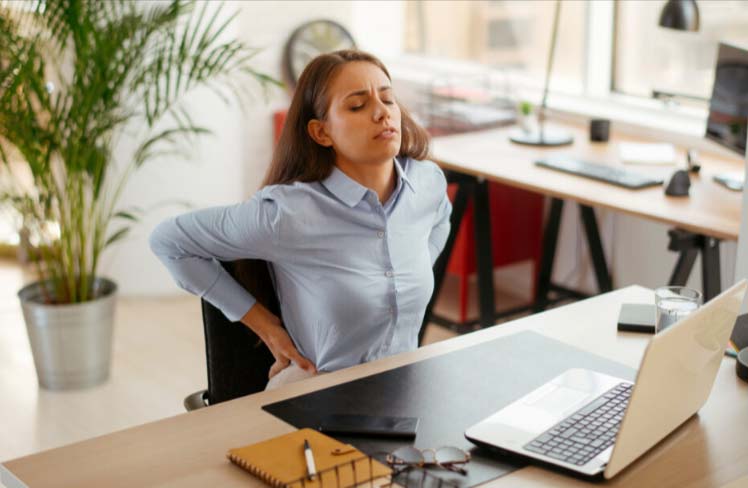 A woman at a desk with a sore back