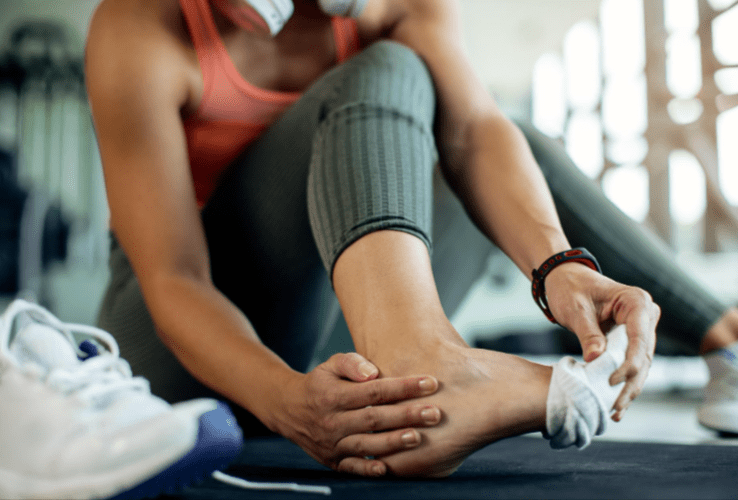 A woman in the gym rubbing a sore ankle