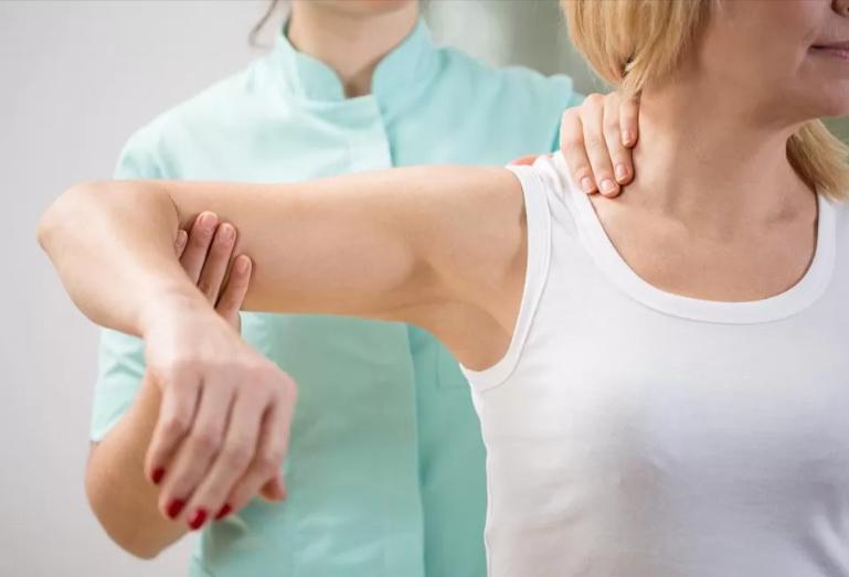 A physical therapists demonstrating shoulder exercises with a woman